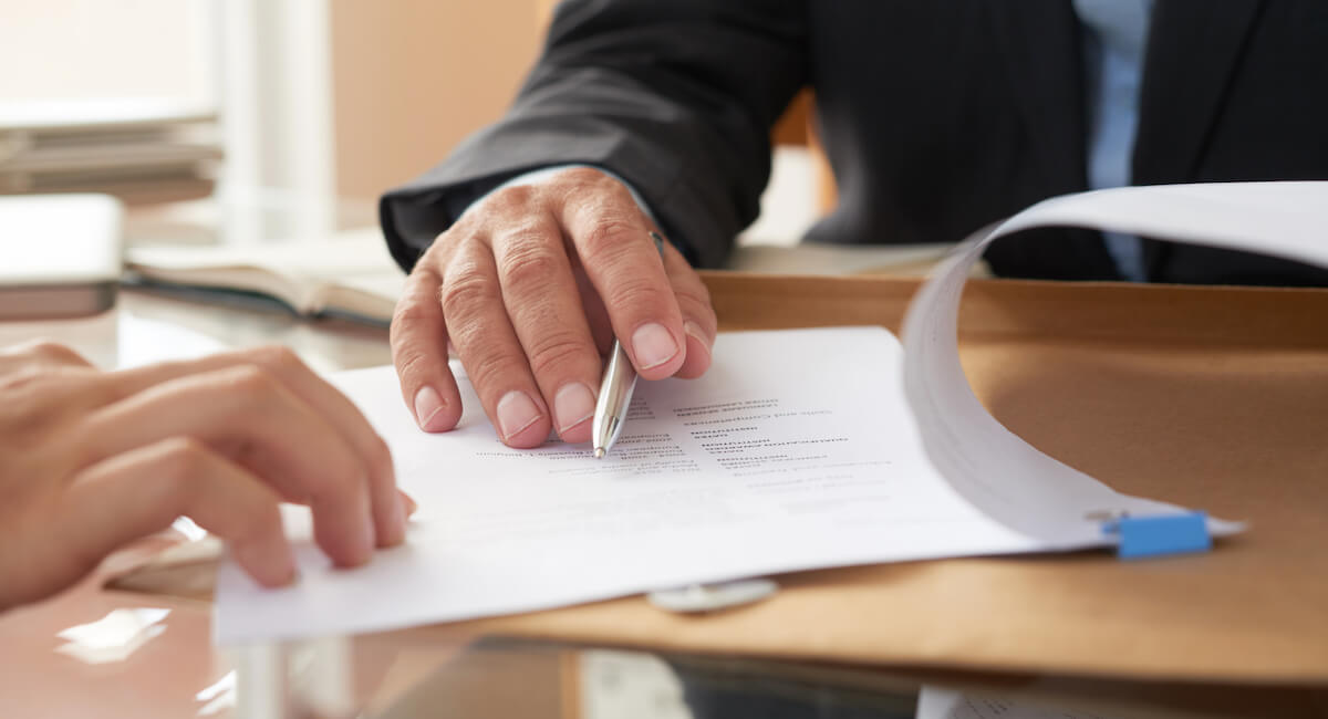 Two hands hovering over a document, with one holding a pen about to sign.