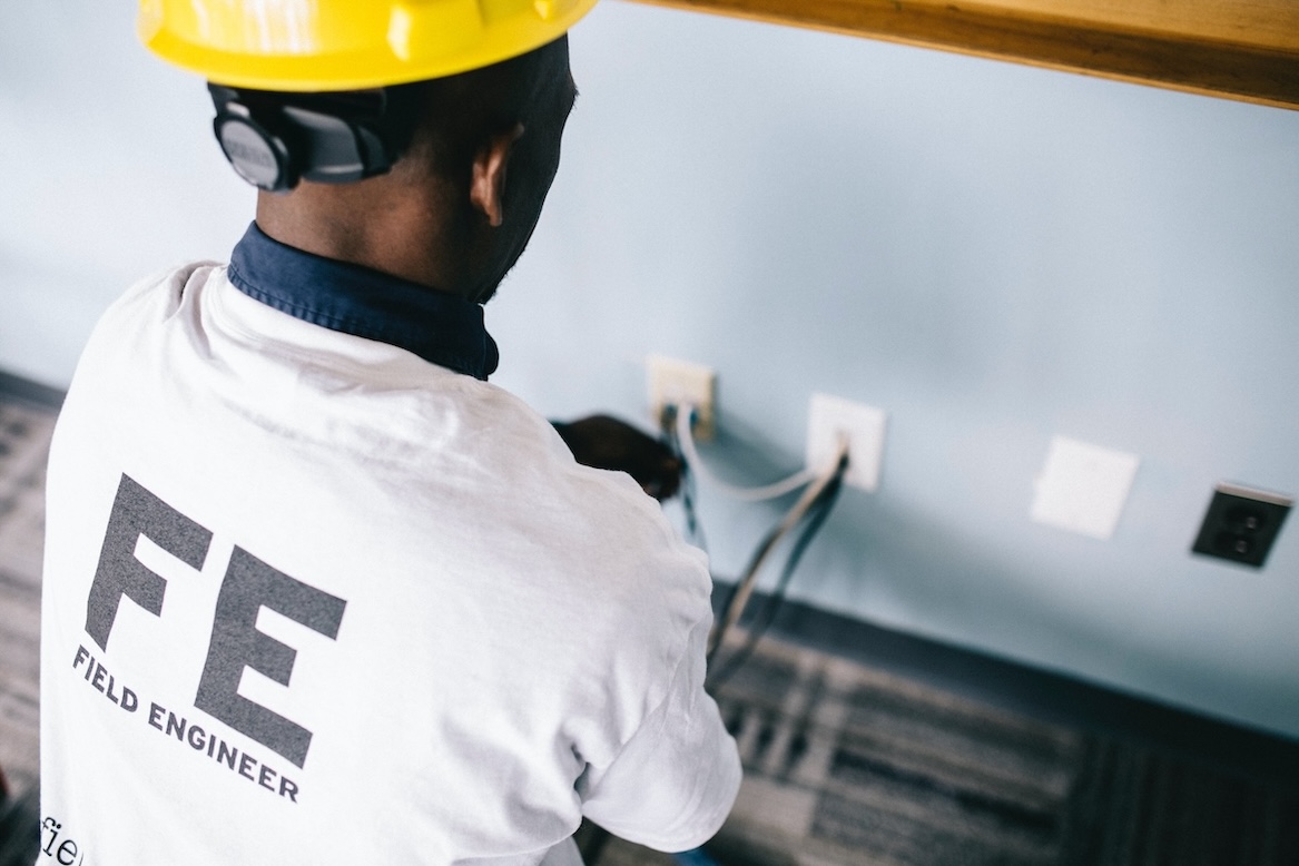 Electrician with construction helmet rewiring an outlet